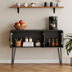 Black sideboard with a coffee maker, apples, and jars against a beige wall.